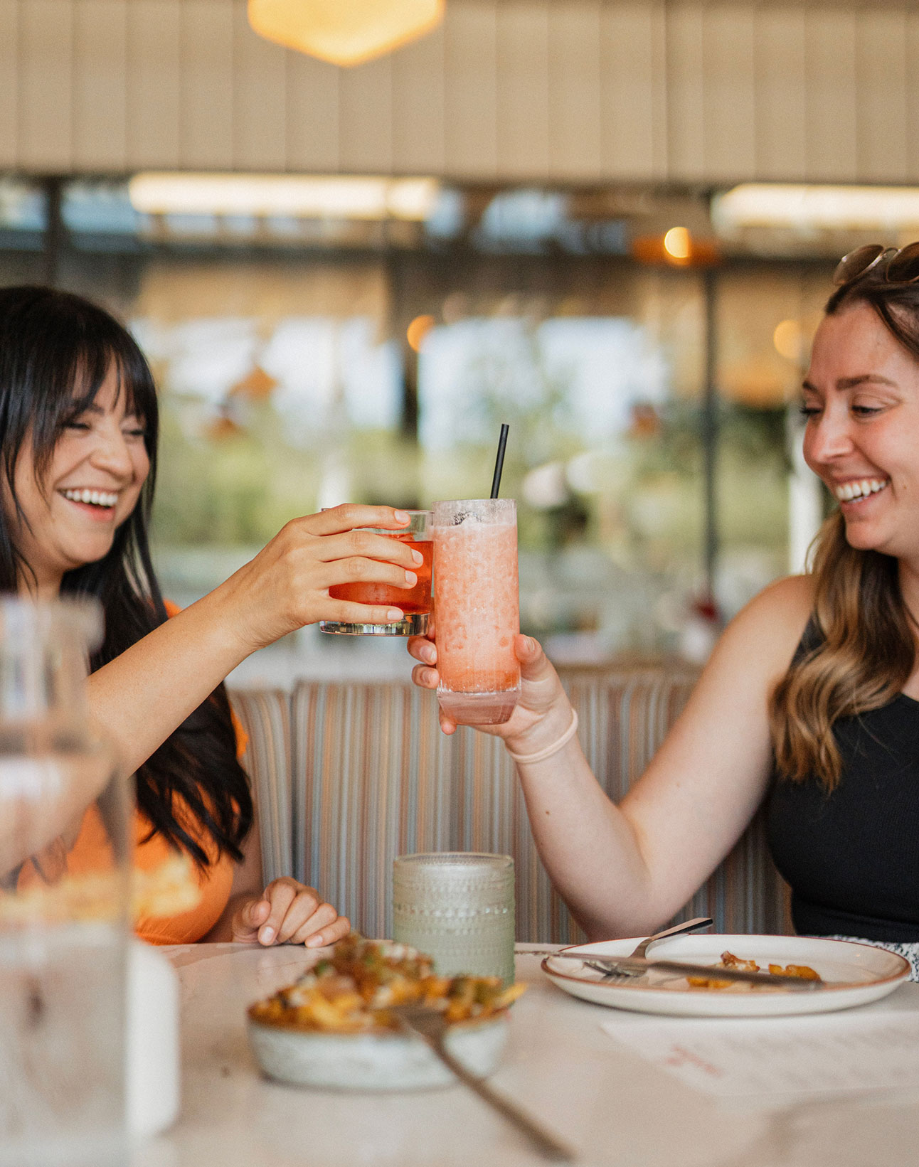 Two women toasting over drinks at Vaquera